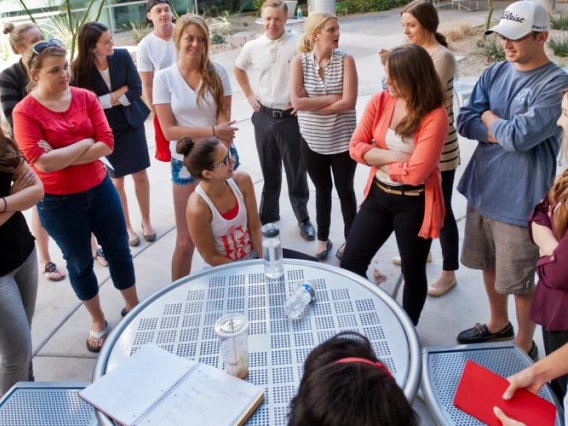 A group of students talking at a table outside.