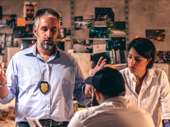 Person with law enforcement badge talking to two colleagues