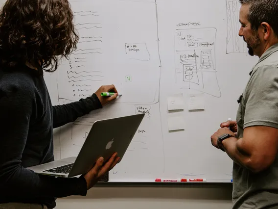 Two professionals collaborating on a whiteboard