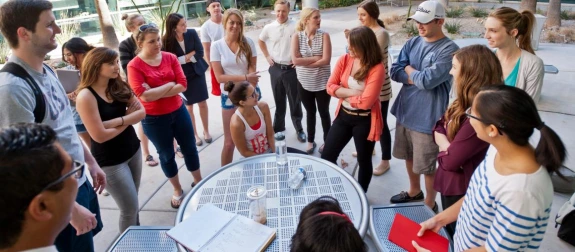 A group of students talking at a table outside.